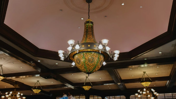 An ornate chandelier hangs from a decorative ceiling.